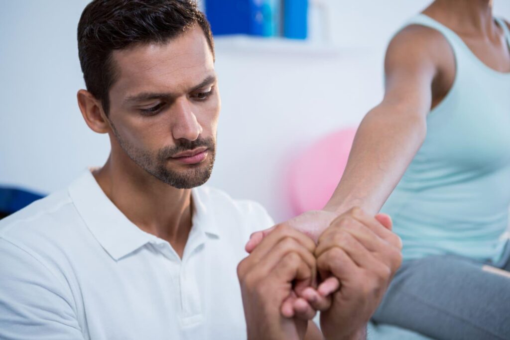 Physiotherapist mobilizing a patient's wrist and forearm during hand rehabilitation