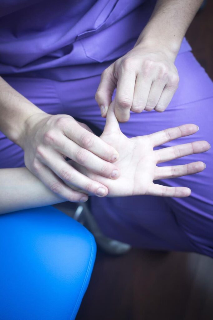 Clinician examining a patient's palm to assess healing factors after carpal tunnel release