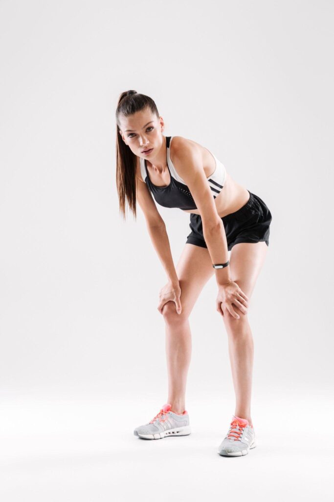 Athlete resting with hands on knees, showing full leg length and proportions